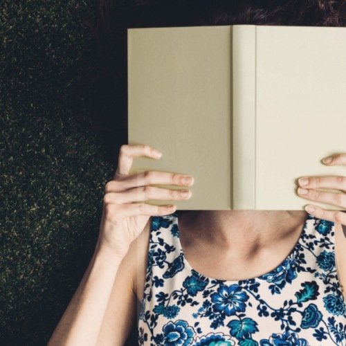 a woman reading a book in grass