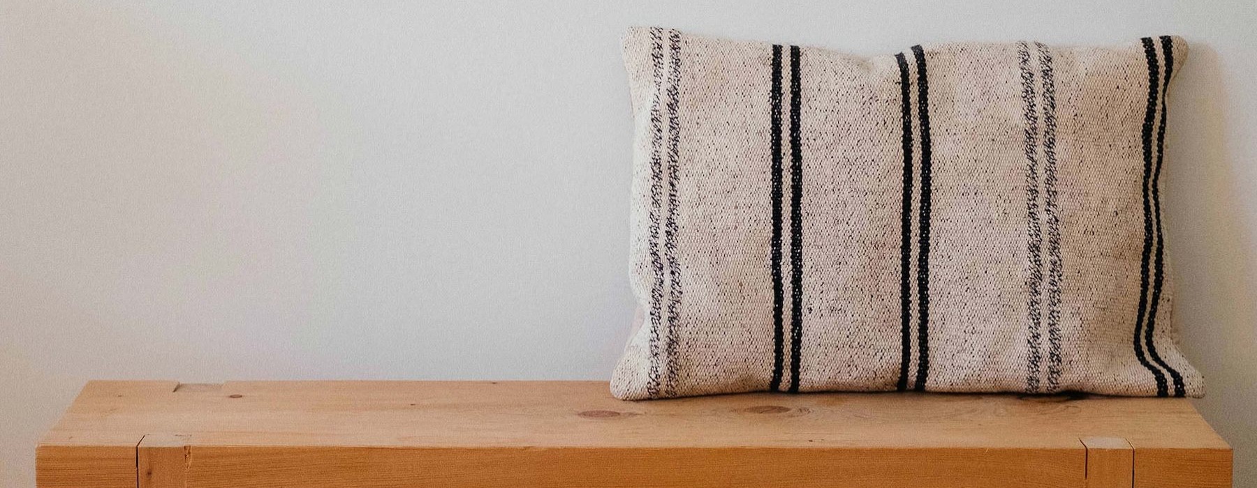 a wooden bench with a striped pillow on it
